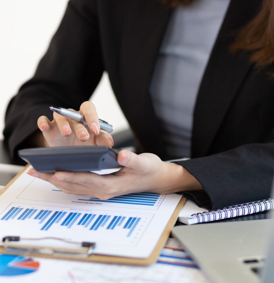 Financial planning and expense accounting concepts. Businesswoman analyzing a business account report using a calculator.